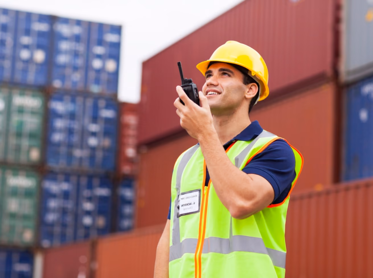 A man wearing a safety vest is talking on a cell phone, appearing engaged in a conversation.