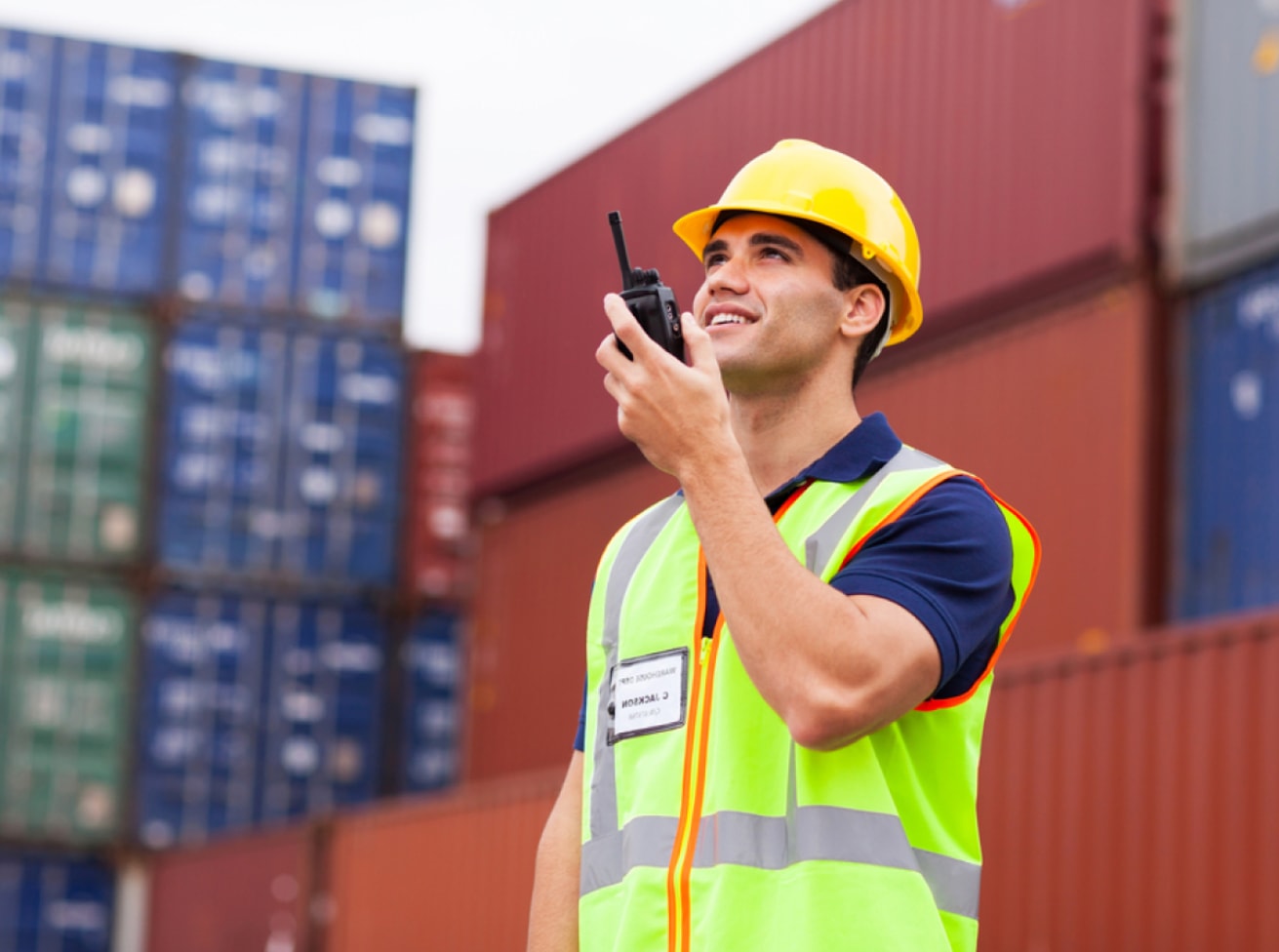 A man wearing a safety vest is talking on a cell phone, appearing engaged in a conversation.  
