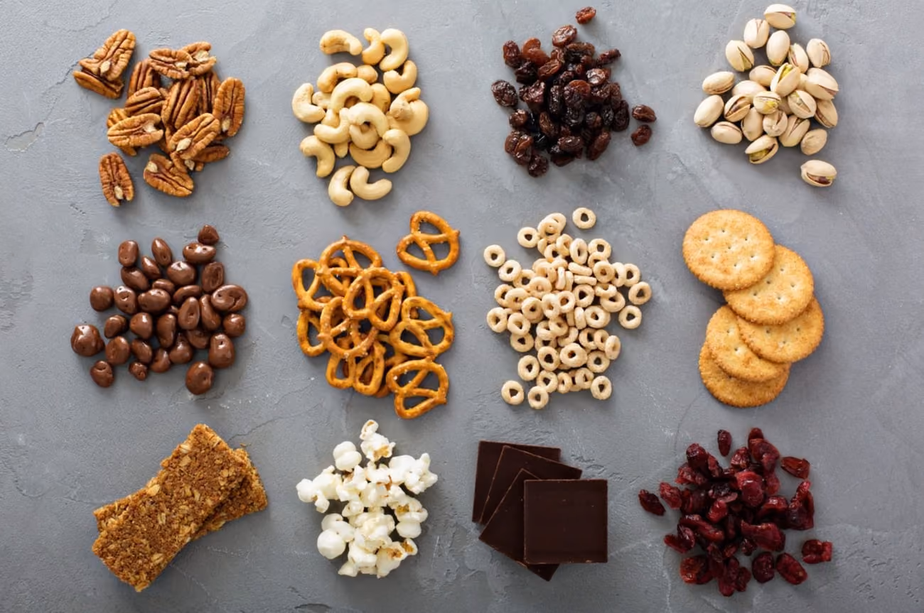A variety of snacks and nuts displayed on a gray surface, showcasing different shapes and textures.