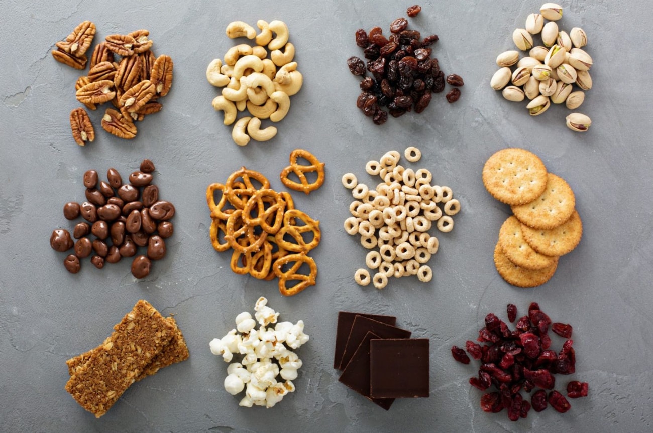 A variety of snacks and nuts displayed on a gray surface, showcasing different shapes and textures.