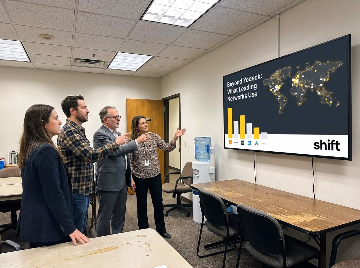 Three people analyze a large screen that features a graph, engaged in discussion about the data presented.