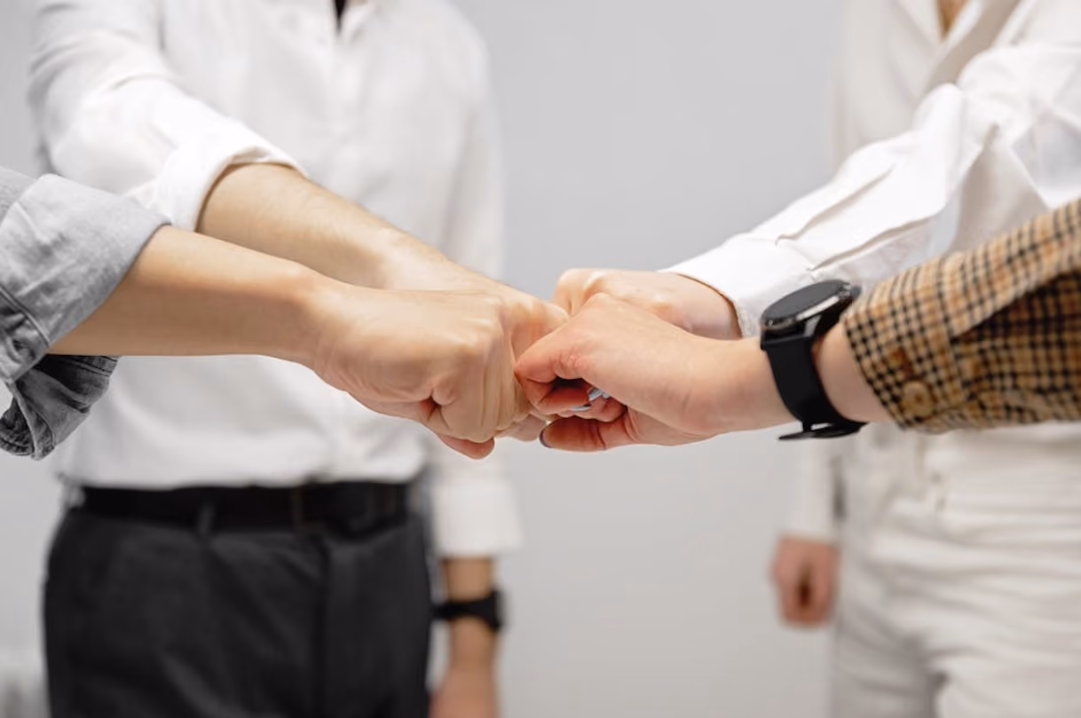 Business team members holding hands in unity, symbolizing collaboration and teamwork in a professional setting.