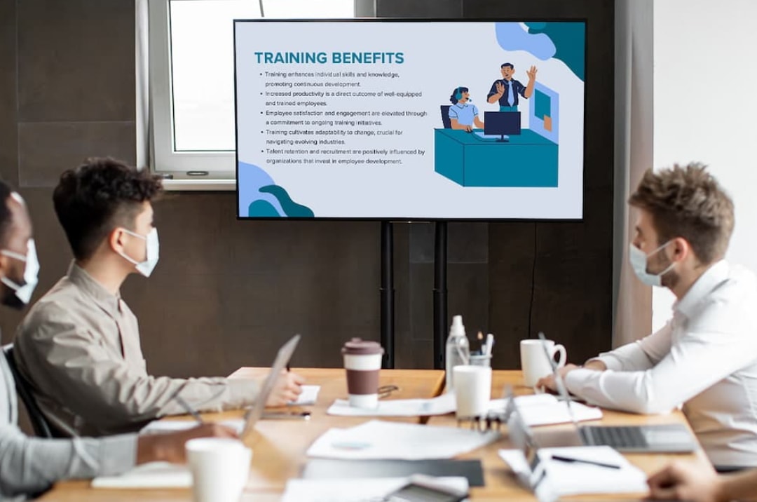 A group of people in a meeting room watching a presentation displayed on a screen. 