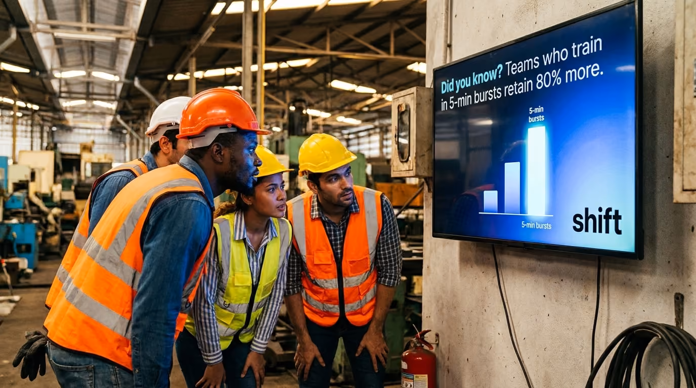 Three individuals in hard hats observe a digital screen, engaged in a discussion about the displayed information. 