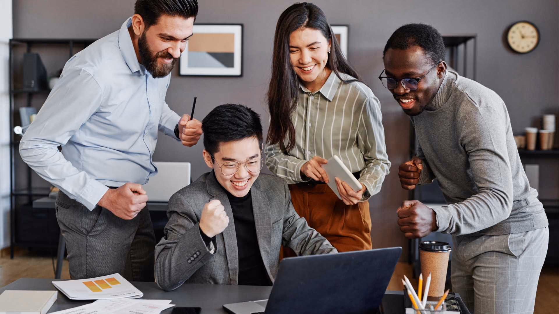 4 people sitting around a computer celebrating 