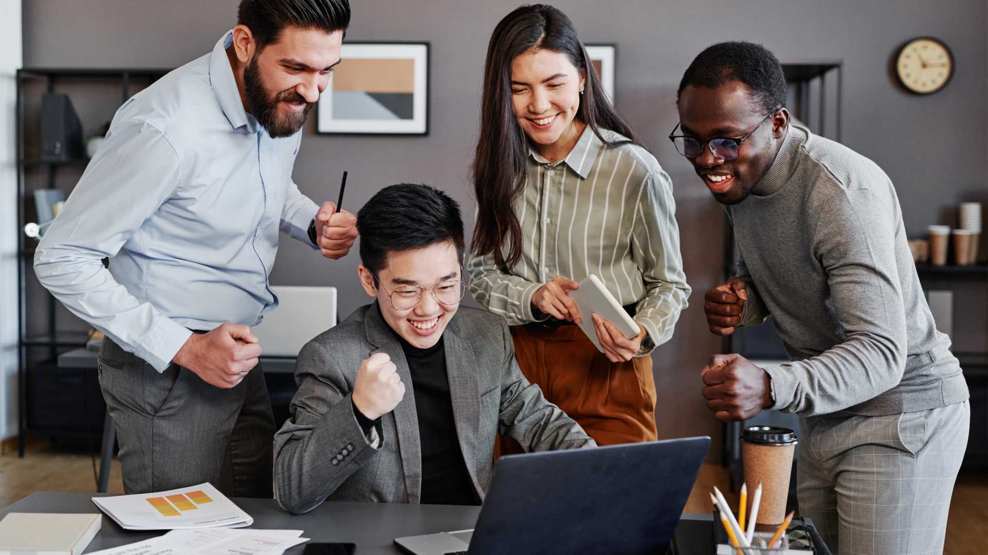 4 people sitting around a computer celebrating