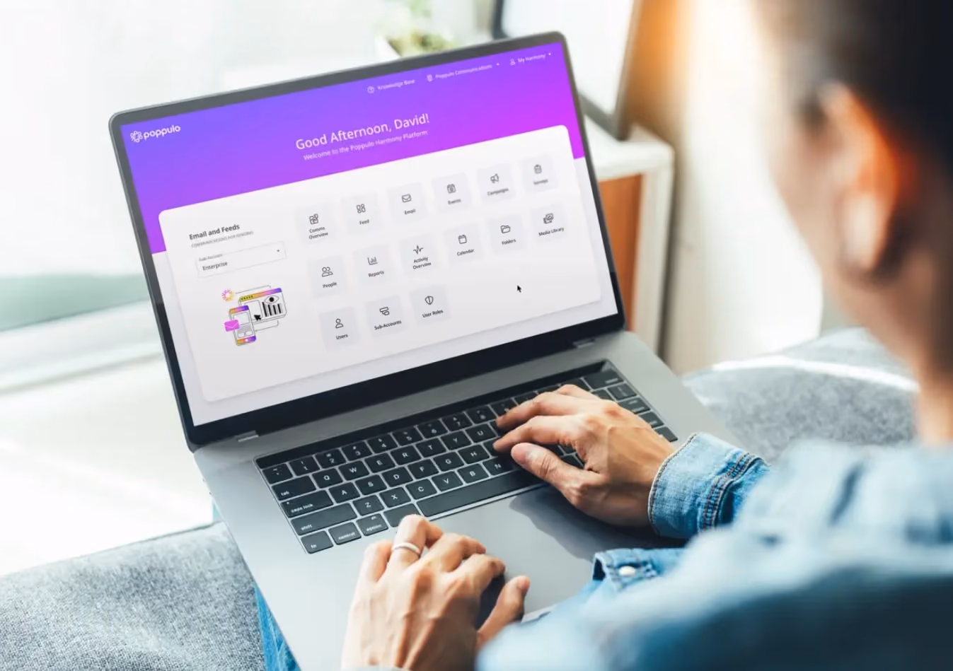 Person using a laptop with a vibrant purple and white dashboard displaying various app icons. They are focused, creating a productive mood.