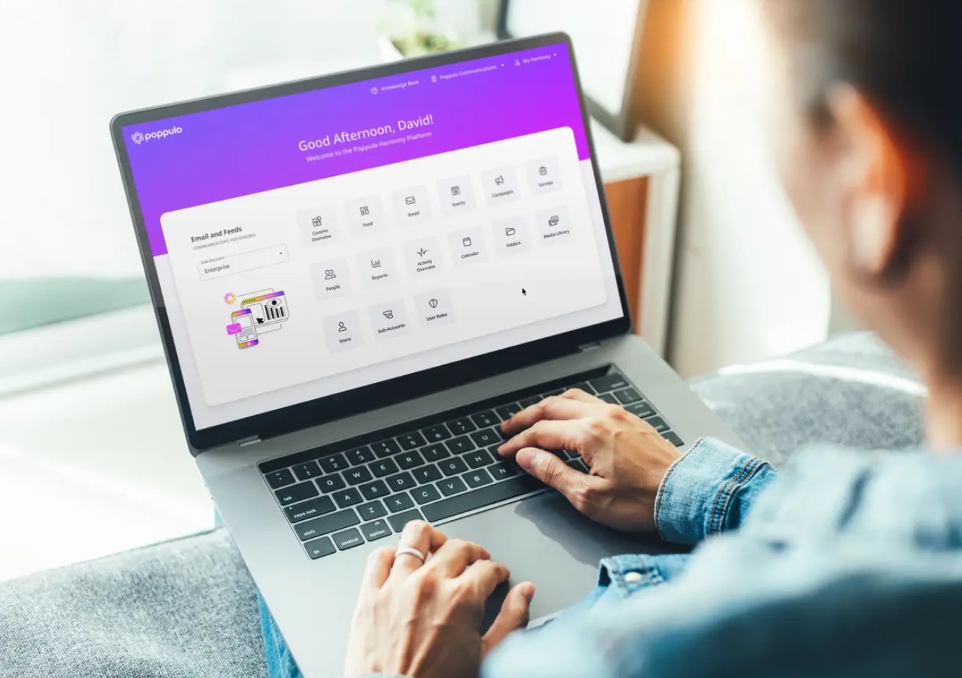 Person using a laptop with a vibrant purple and white dashboard displaying various app icons. They are focused, creating a productive mood.