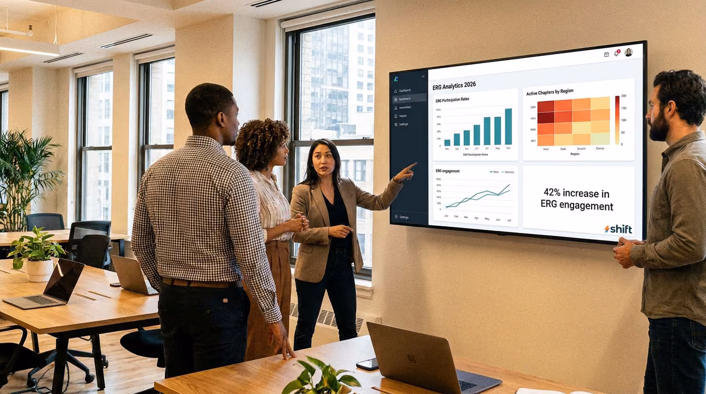 A group of four diverse professionals in an office watch a presentation on a large screen showing colorful graphs and charts, discussing analytics.