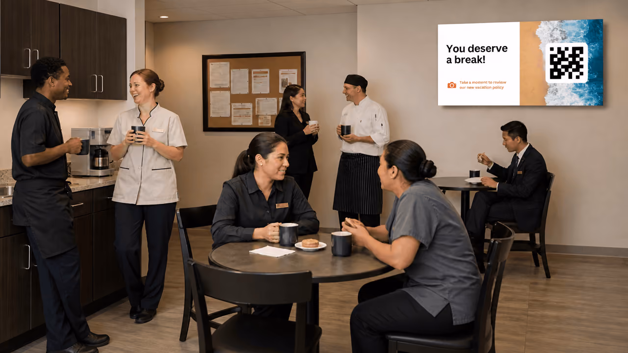 Hotel workers sitting in a break room engaging in conversation with a digital screen in the background
