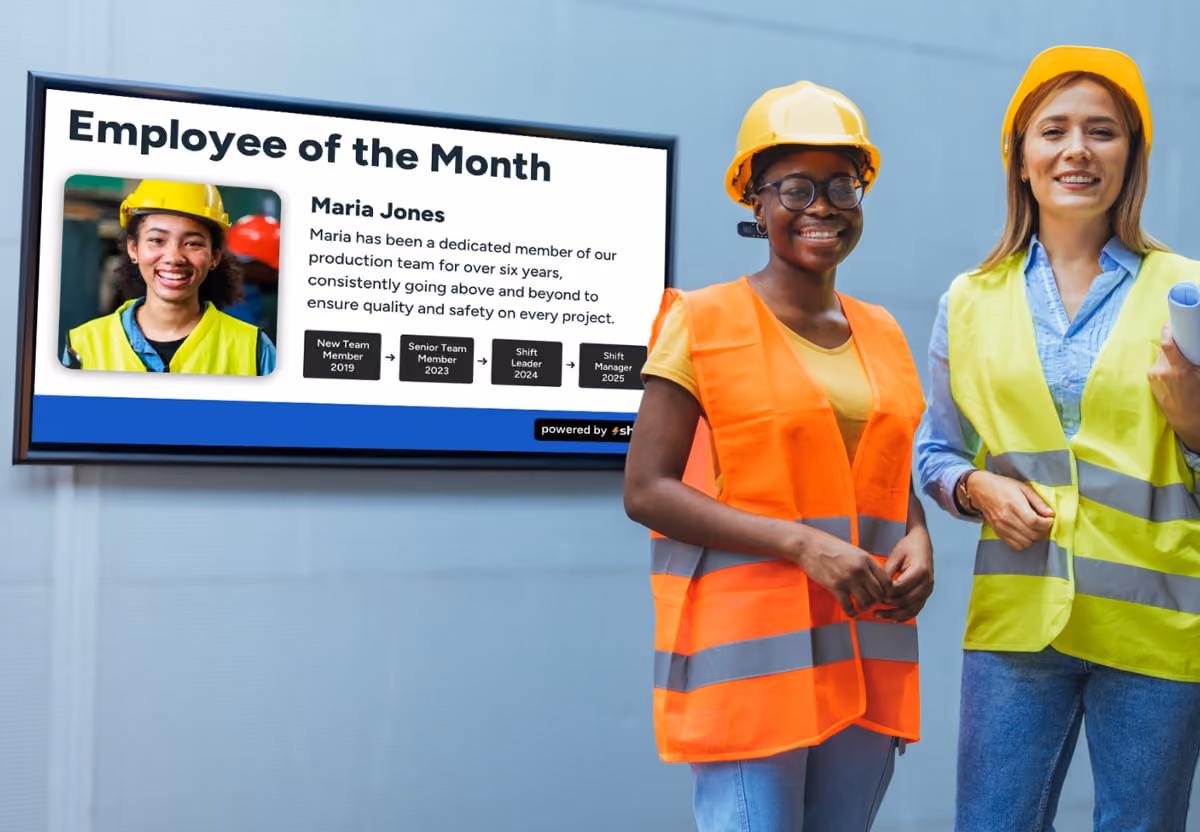 A group photo of the employees of the month, smiling and holding certificates in a well-lit office setting.
