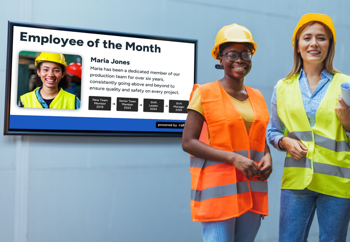 A group photo of the employees of the month, smiling and holding certificates in a well-lit office setting.