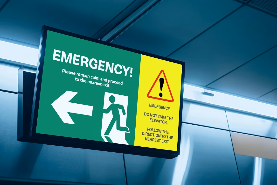 Emergency exit sign with arrow and warning: "Do not take the elevator. Follow the direction to the nearest exit.