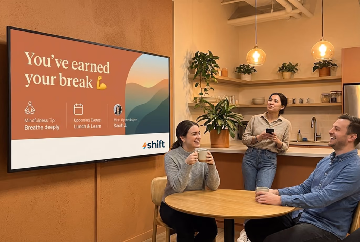 Three people seated at a table, watching a TV screen in a casual setting.