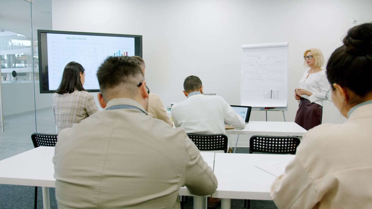 A diverse group of professionals engaged in discussion around a whiteboard in a meeting room