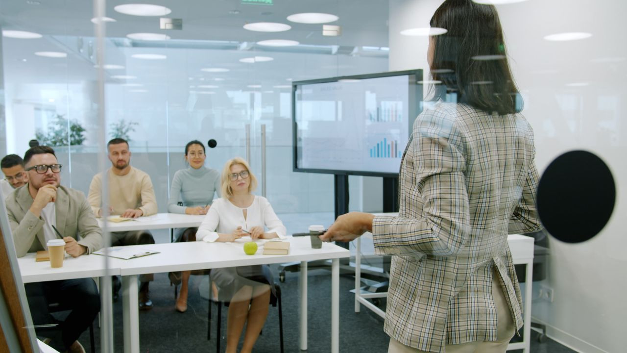 Several individuals collaborating in a meeting room, focused on a whiteboard filled with notes and diagrams