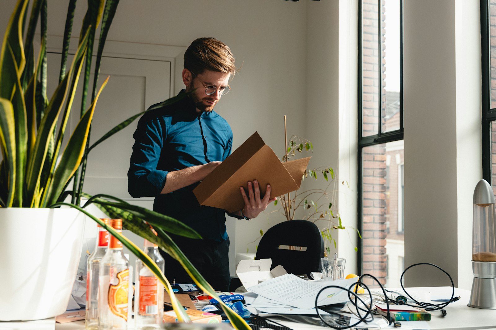 Man standing in an office holding a box of belongings after his last day