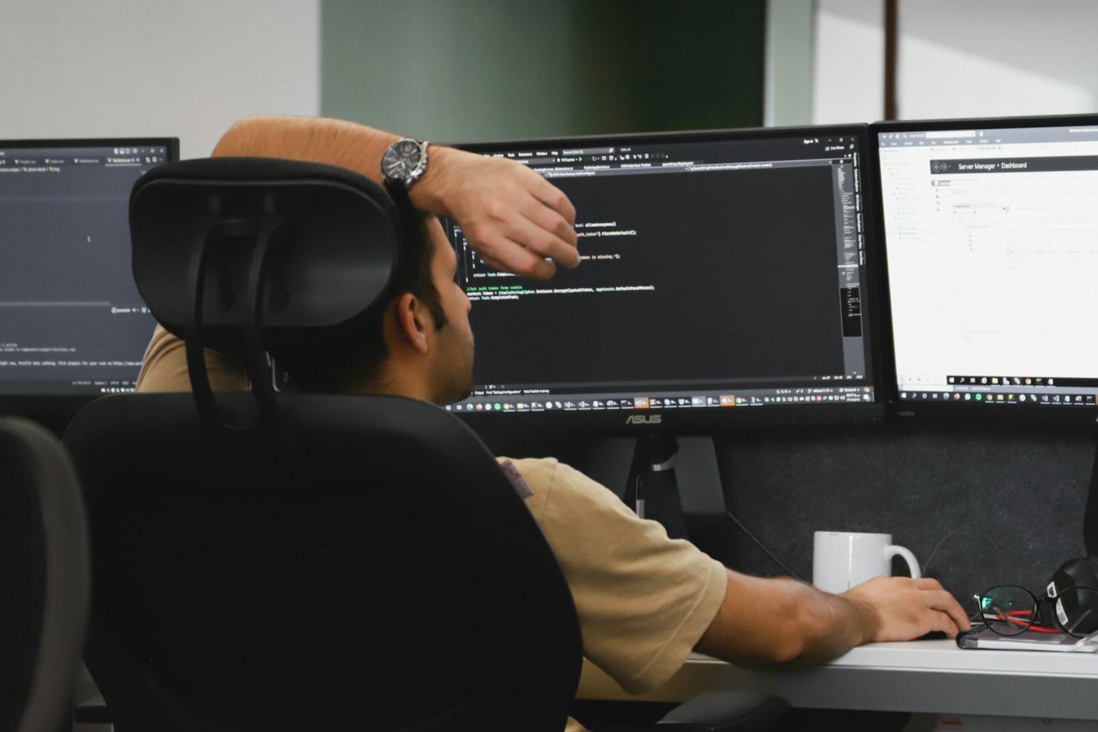 DevOps engineer working in front of two computer monitors managing infrastructure