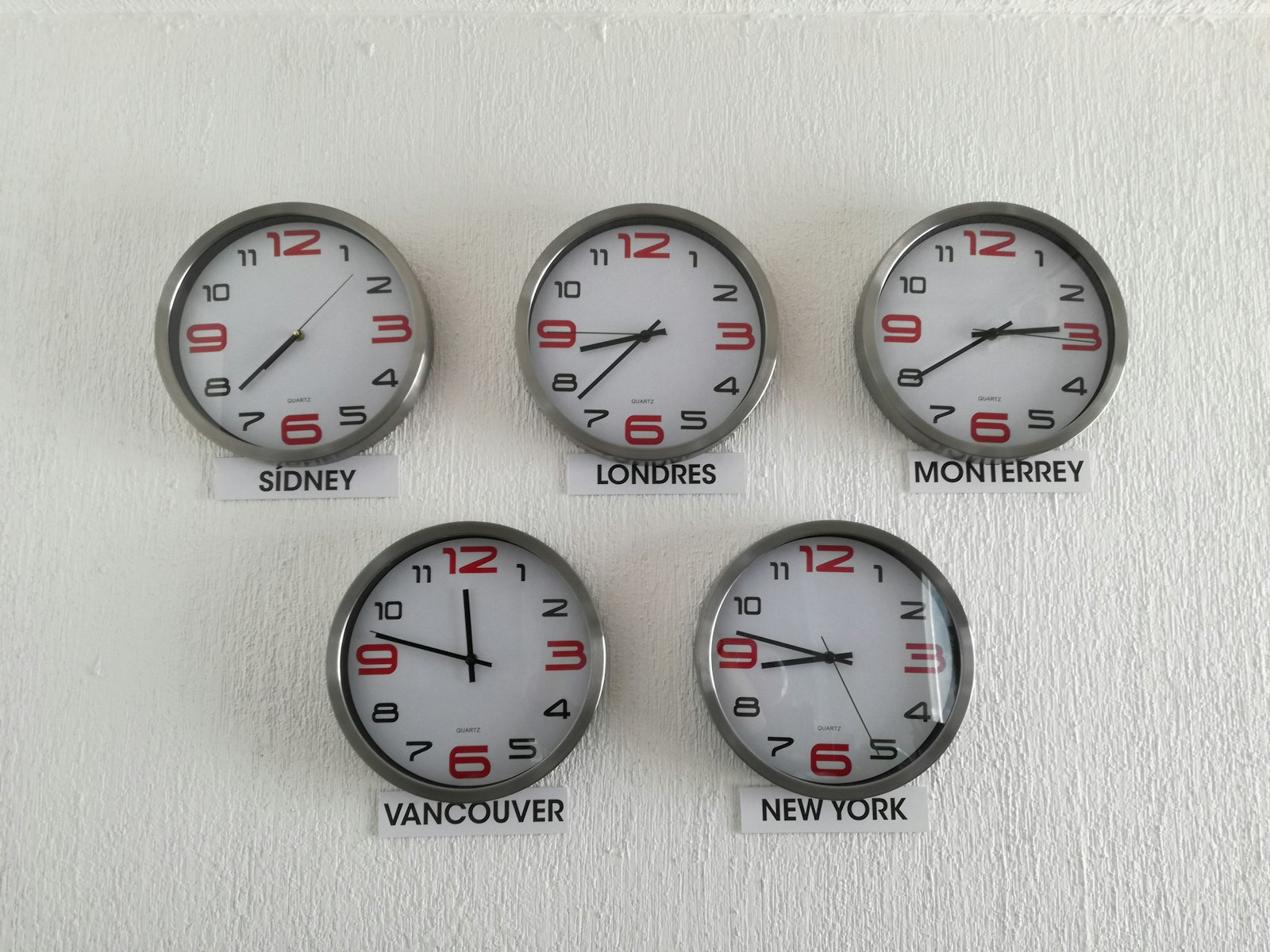 Row of wall clocks showing different time zones, the core idea behind nearshore staffing