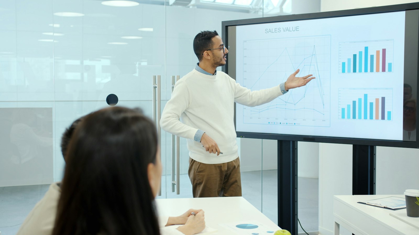Man presenting charts on a large screen while building a business case for leadership