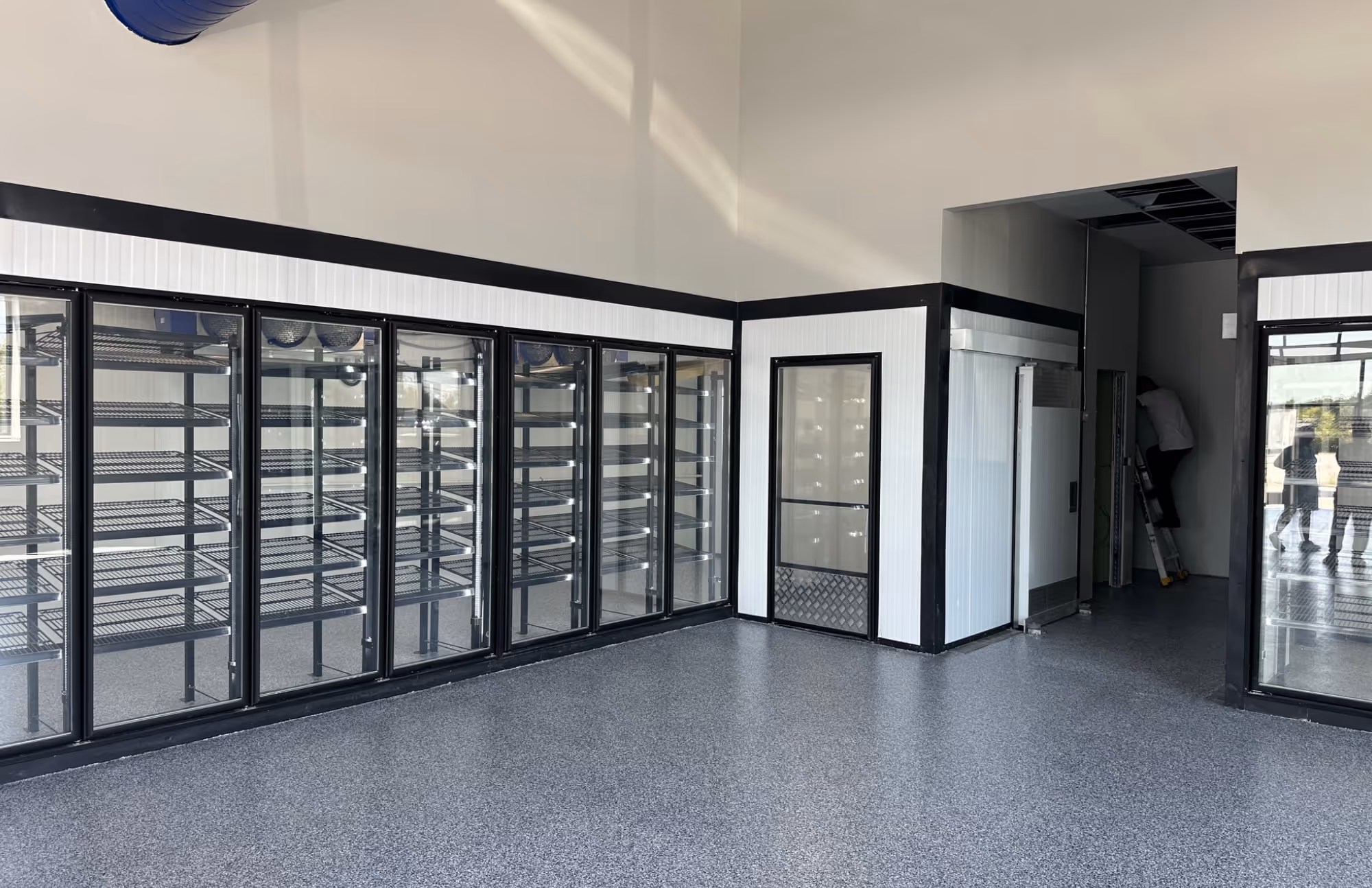 Walk-in cooler with black-frame reach-in glass doors empty