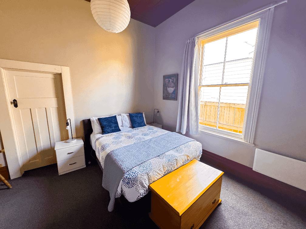Accommodation in Gisborne Constables Quarters 4 bedroom house, photo is of middle room, showing queen & single bed