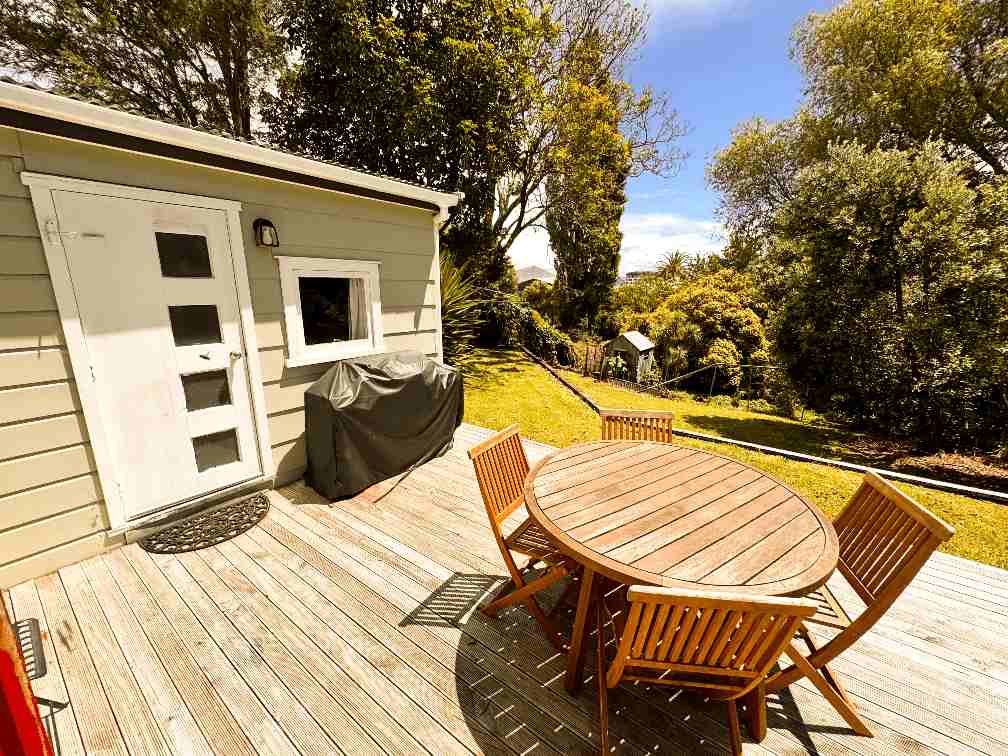 Outdoor deck at Harris Hideaway, 2-bedroom accommodation in Gisborne — photo shows a table, chairs, and BBQ setup.