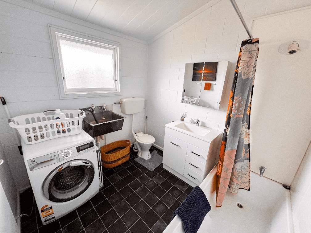 Accommodation in Gisborne Rutene Road Retreat 1 bedroom house, photo is of bathroom which shows the shows over bath, laundry and vanity