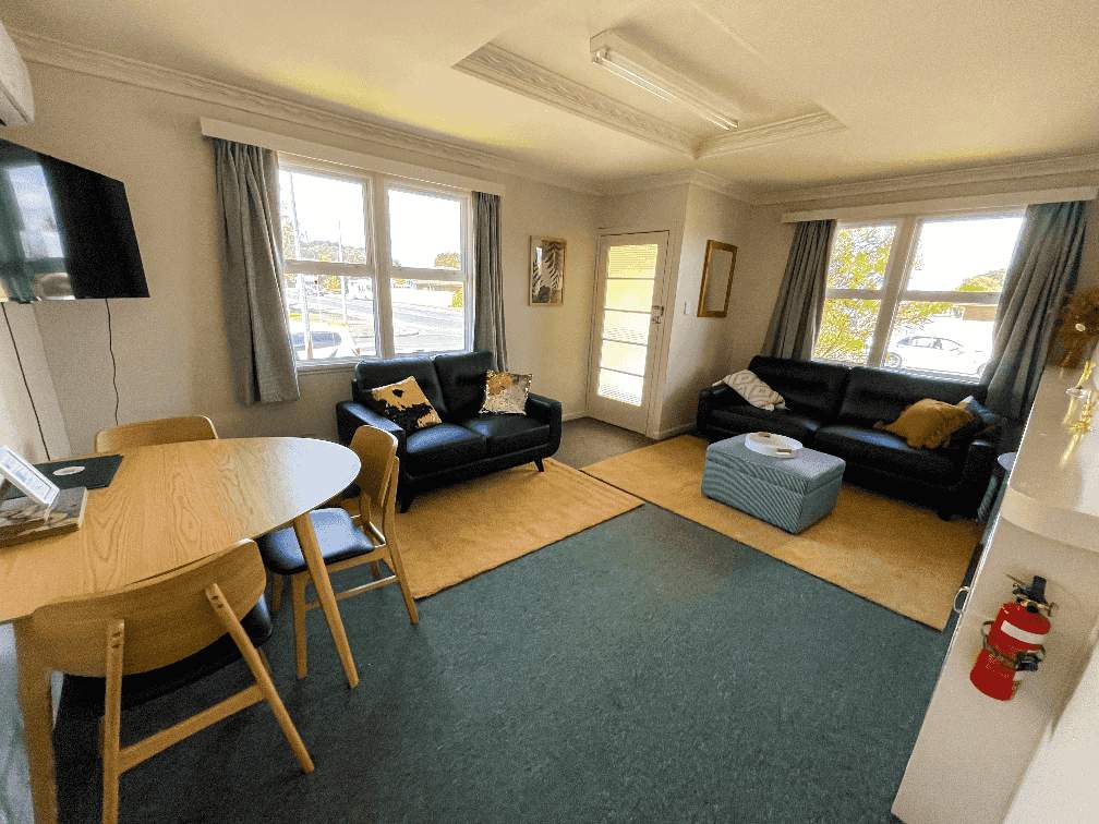 Lounge area of The Ascot Flat 1, a comfortable 2-bedroom holiday flat by Accommodation in Gisborne, featuring seating, dining table, and TV.