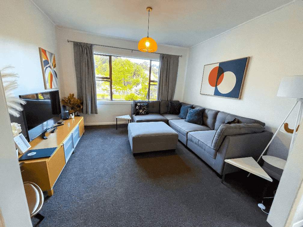 Lounge area at Russell Rumpus Retreat in Gisborne, featuring a large sectional sofa, TV, and bright modern decor—perfect for relaxing during your stay.