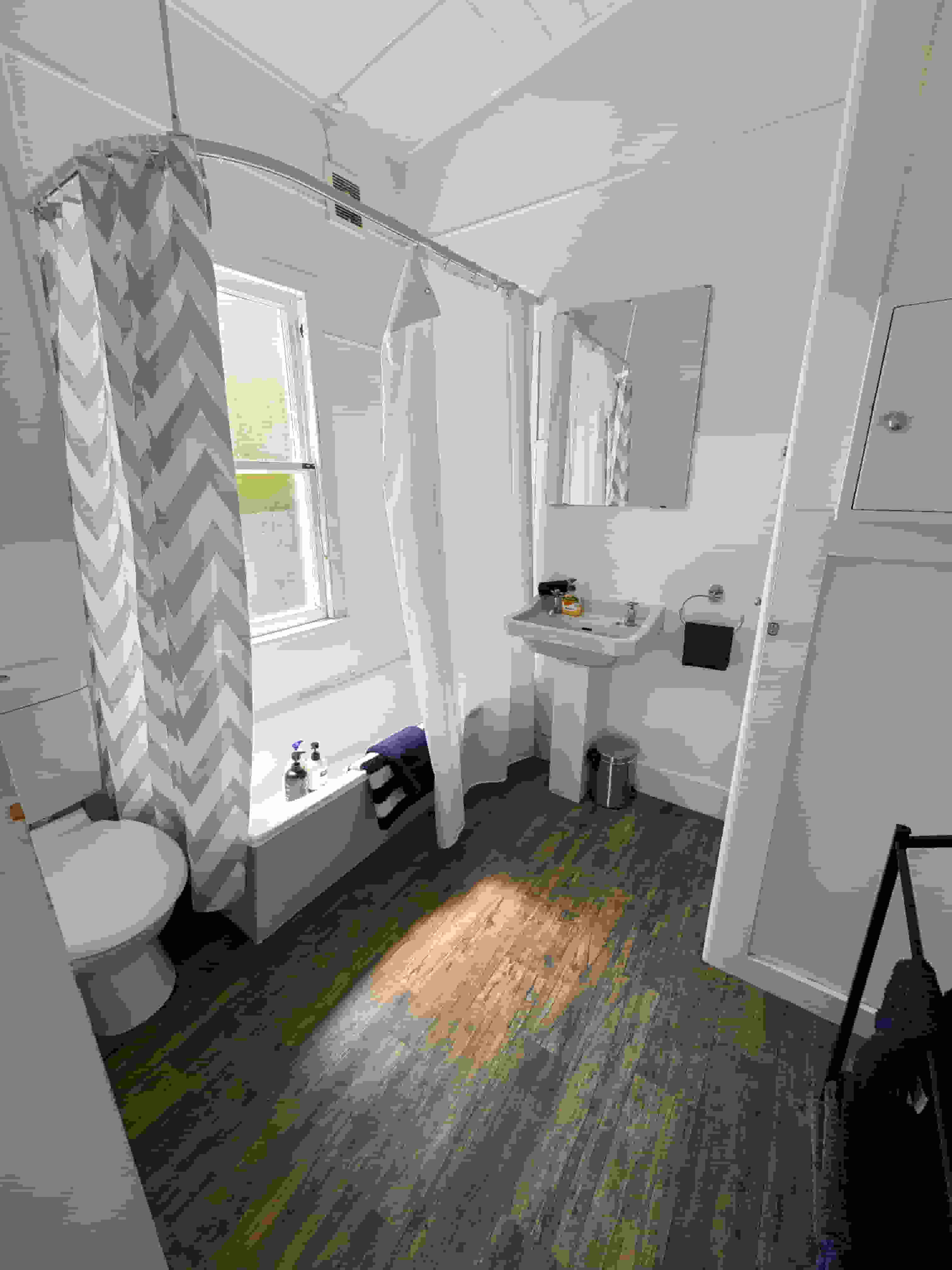 Accommodation in Gisborne Constables Quarters 4 bedroom house, photo is of bathroom which shows the shows over bath, laundry and vanity