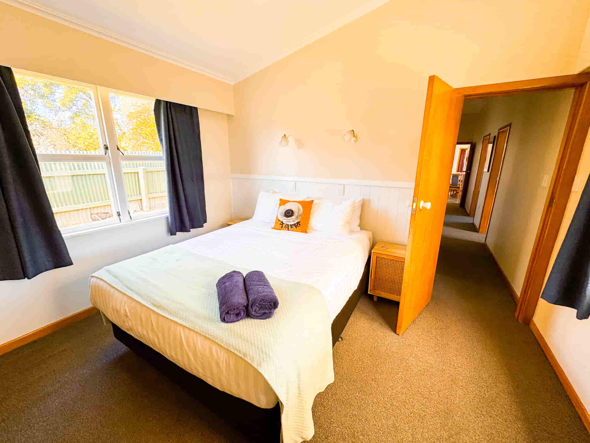 Accommodation in Gisborne Esplanade Easy Escape 3 bedroom house, photo is end room bedroom 3, showing queen bed and bedside tables