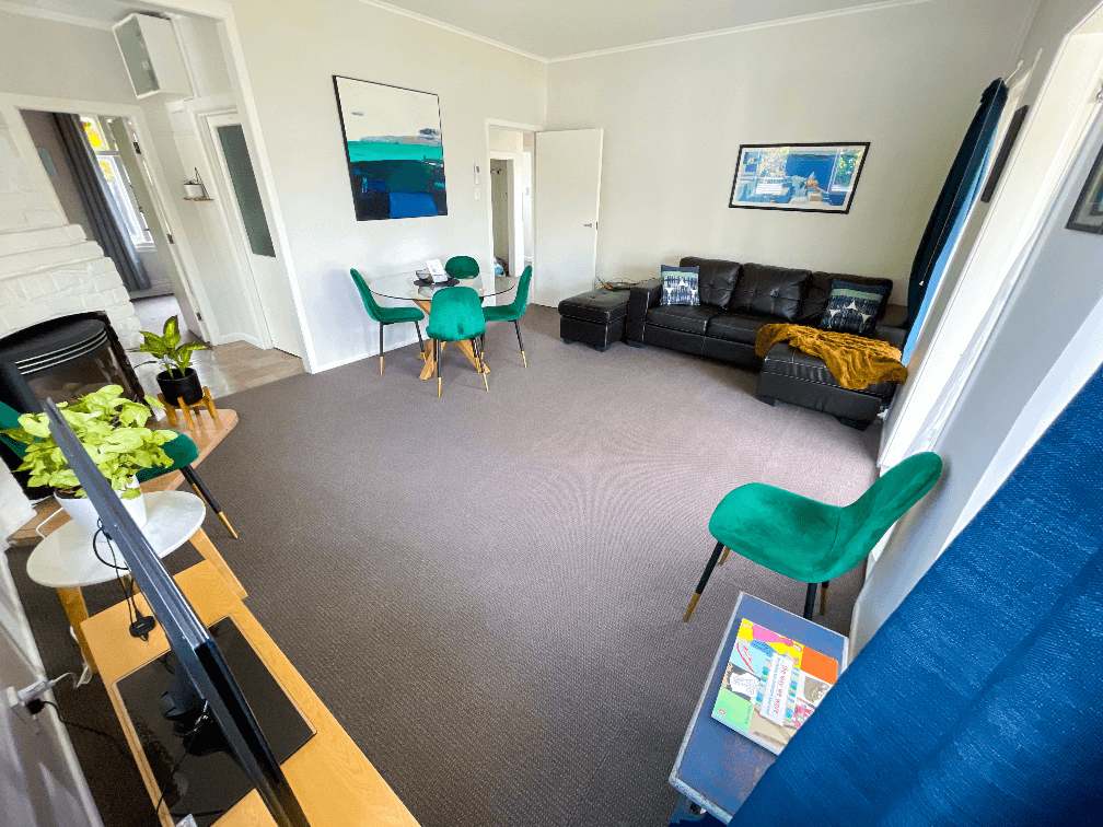 Accommodation in Gisborne Stafford Stays 3 bedroom house, photo is of lounge area showing back of tv, dinning table and chairs and couch