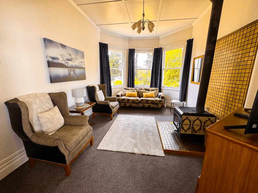 Light-filled lounge of Aberdeen Villa with a fireplace, TV and ample seating.