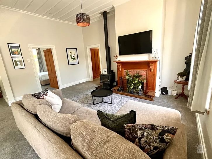 Lounge area at The Clifford in Gisborne, featuring a large sectional sofa, TV, and bright neutral decor—perfect for relaxing during your stay.