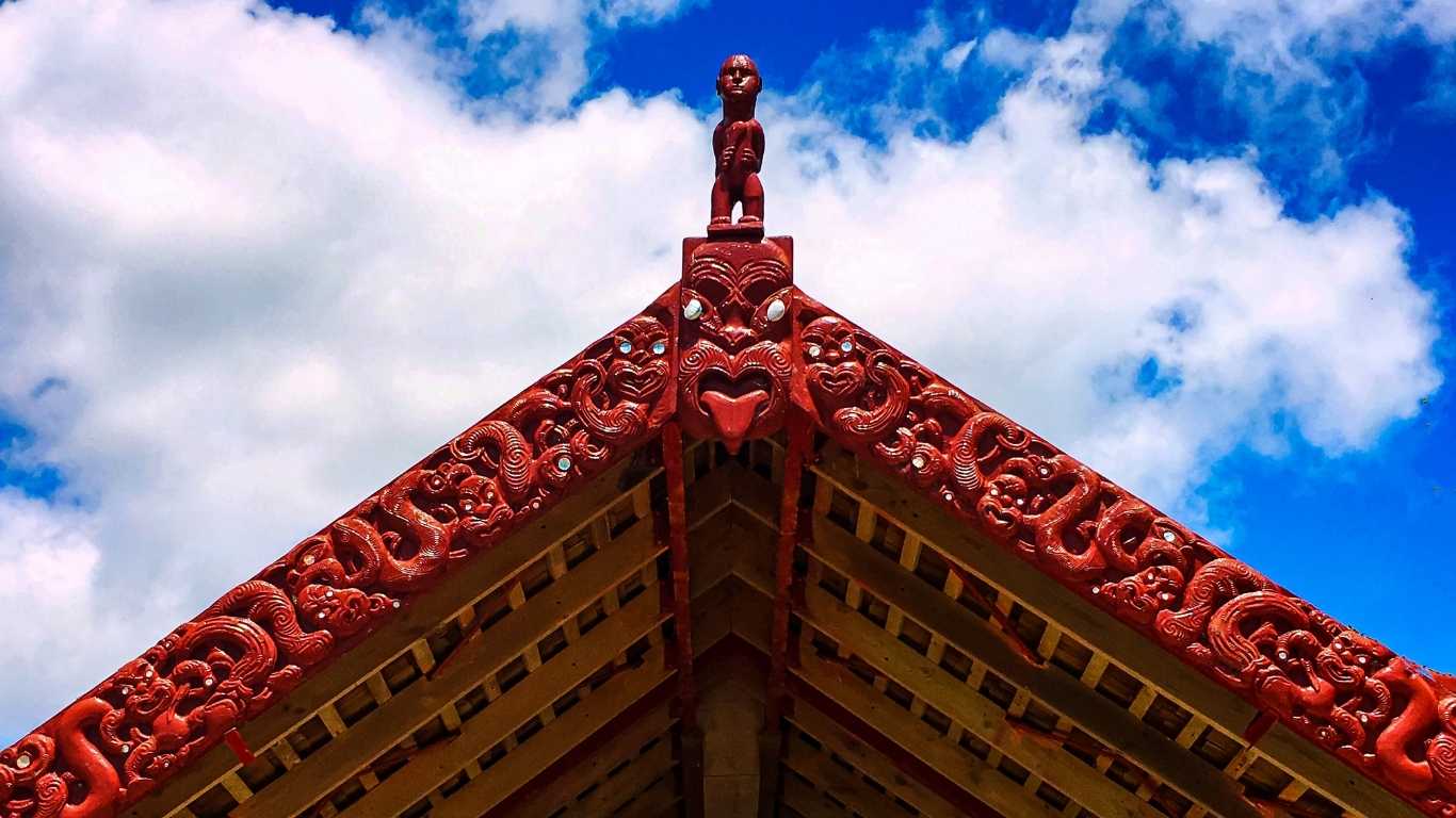 Traditional Māori whakairo carvings on a meeting house gable with tekoteko figure, symbolising heritage and community in Gisborne