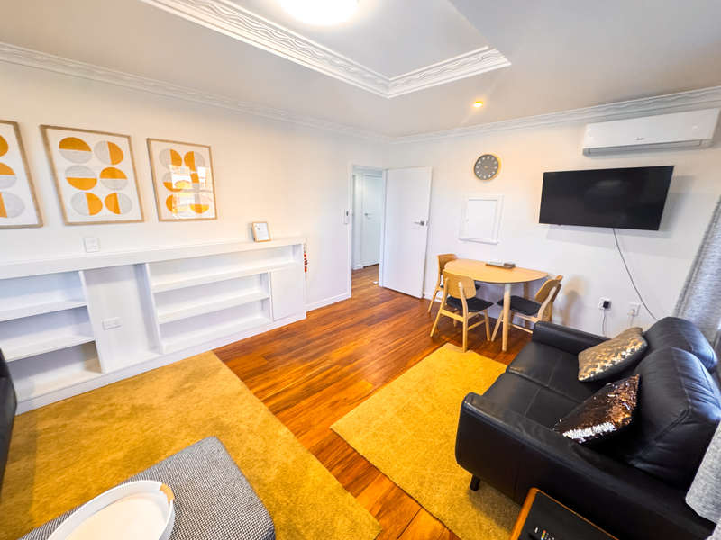 Lounge area of The Ascot Flat 1, a comfortable 2-bedroom holiday flat by Accommodation in Gisborne, featuring seating, dining table, and TV.