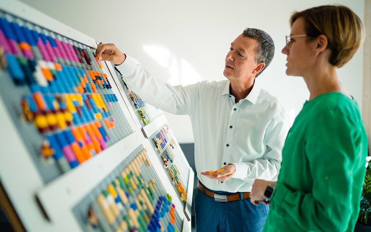 Mitarbeiter verwenden Lego-Steine auf einer Tafel zur Visualisierung von Projekten