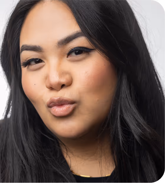 Close-up portrait of a woman with long black hair making a kissy face.