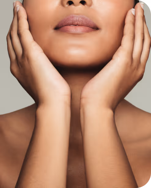 Close-up of a woman gently holding her face with both hands, showcasing smooth skin and natural lips.