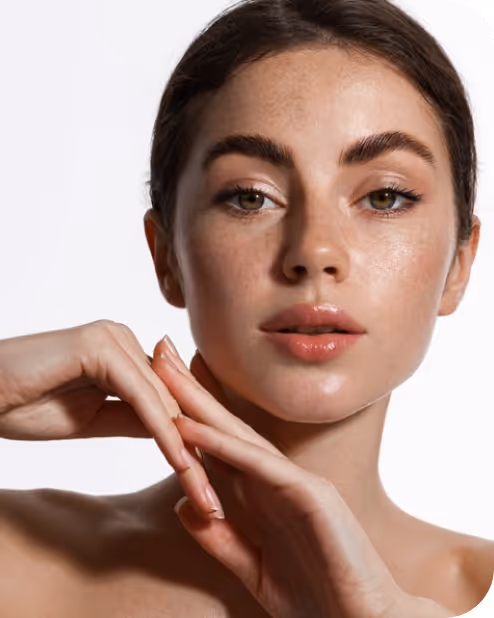 Close-up of a woman with clear skin posing with her hands near her face against a white background.
