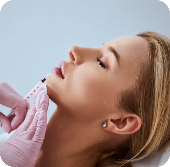 Close-up of a woman receiving a cosmetic injection in her chin from a gloved professional.