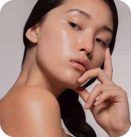 Close-up of a woman with smooth, glowing skin gently touching her face.