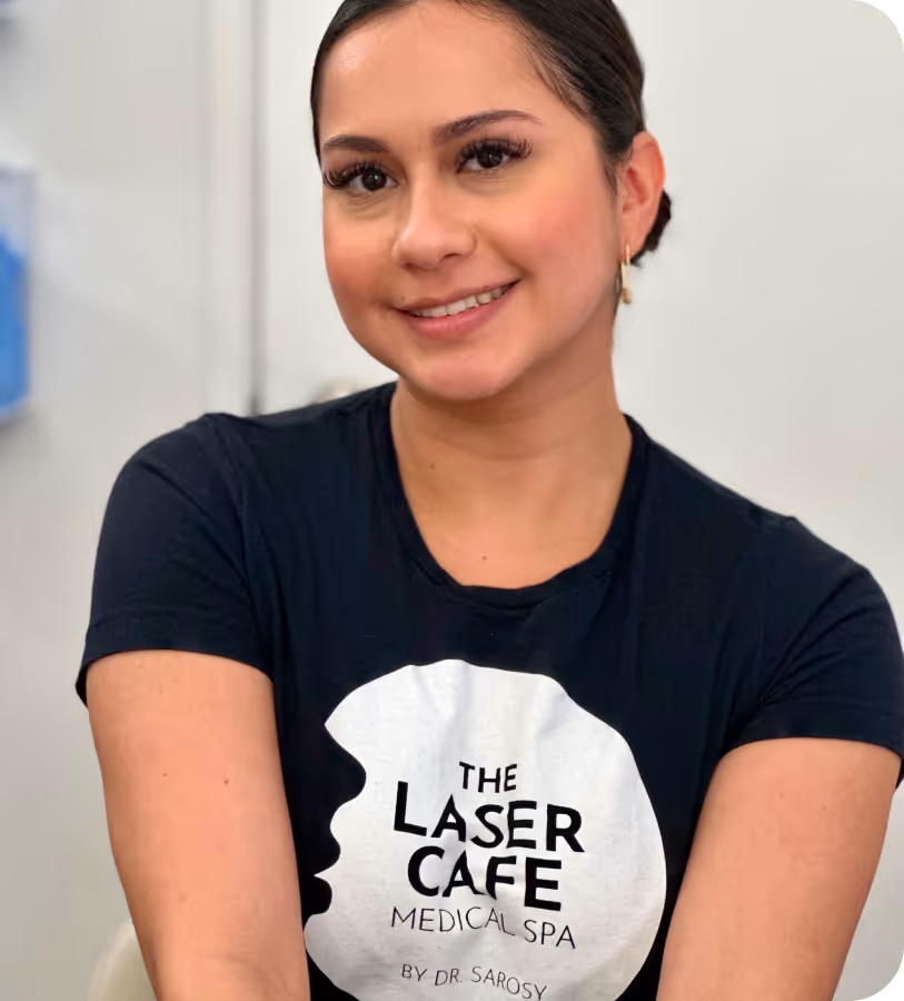 Smiling woman with dark hair wearing a black t-shirt that reads 'The Laser Cafe Medical Spa by Dr. Sarosy'.