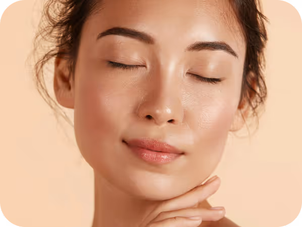 Close-up of a woman with clear skin and closed eyes gently touching her chin.