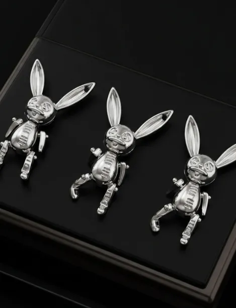 Three silver bunny-shaped charms with movable limbs displayed on a black surface.