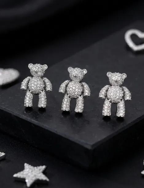 Three silver teddy bear-shaped charms encrusted with small diamonds on a black surface.
