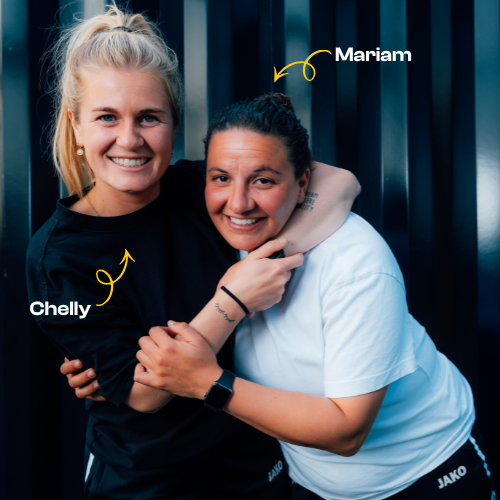 Een sportleraar leidt een groep kinderen in een gymzaal die hun duimen opheffen terwijl ze naar boven kijken.