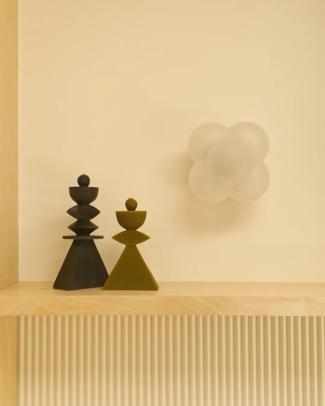 Deux bougies artisanales aux formes graphiques et aux teintes chaudes rehaussent l'ambiance décorative de cette pièce.