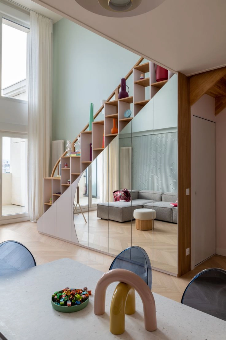 Les placards toute hauteur intégrés sous l'escalier de ce salon se fondent dans le décor grâce à leurs façades en miroirs.